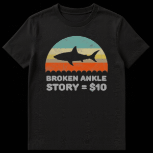 Vintage retro sunset t-shirt design with a shark silhouette and text reading Broken Ankle Story equals 10 dollars on Black t-shirt