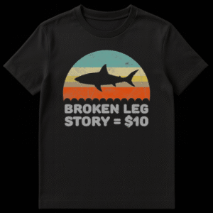 Retro sunset graphic with black shark silhouette and text reading Broken Leg Story equals 10 dollars on Black t-shirt