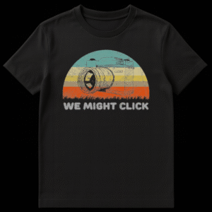 Vintage style t-shirt design featuring a sketch of an SLR film camera in front of a retro striped sunset with the text We Might Click below it on Black t-shirt