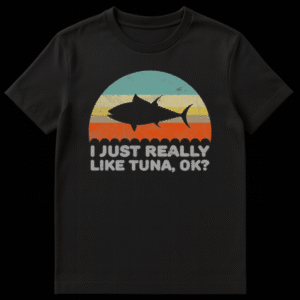 Black t-shirt with a distressed semi-circle sunset graphic in blue, cream, beige, and orange-red stripes, featuring a black tuna fish silhouette. Below, a scallop border and the text 'I JUST REALLY LIKE TUNA, OK?' in light gray distressed font. on Black t-shirt
