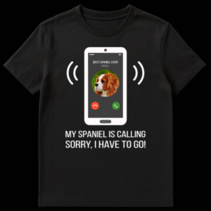 Humorous t-shirt design with a white smartphone displaying an incoming call from 'BEST SPANIEL EVER' with a Cavalier King Charles Spaniel profile picture, and text 'MY SPANIEL IS CALLING SORRY, I HAVE TO GO!' on Black t-shirt