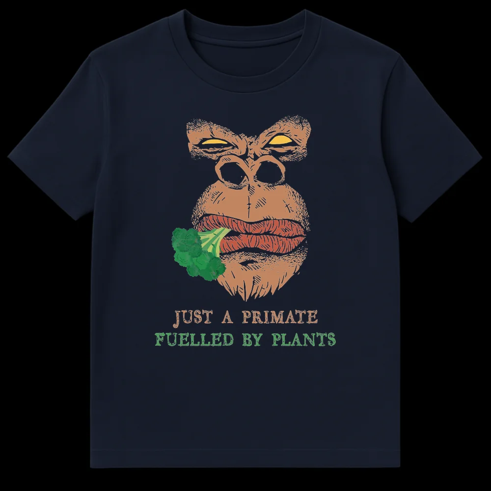 Distressed comic style graphic t-shirt featuring an intense gorilla eating broccoli with text 'JUST A PRIMATE FUELLED BY PLANTS' in tan and green colors. on Navy Blue t-shirt